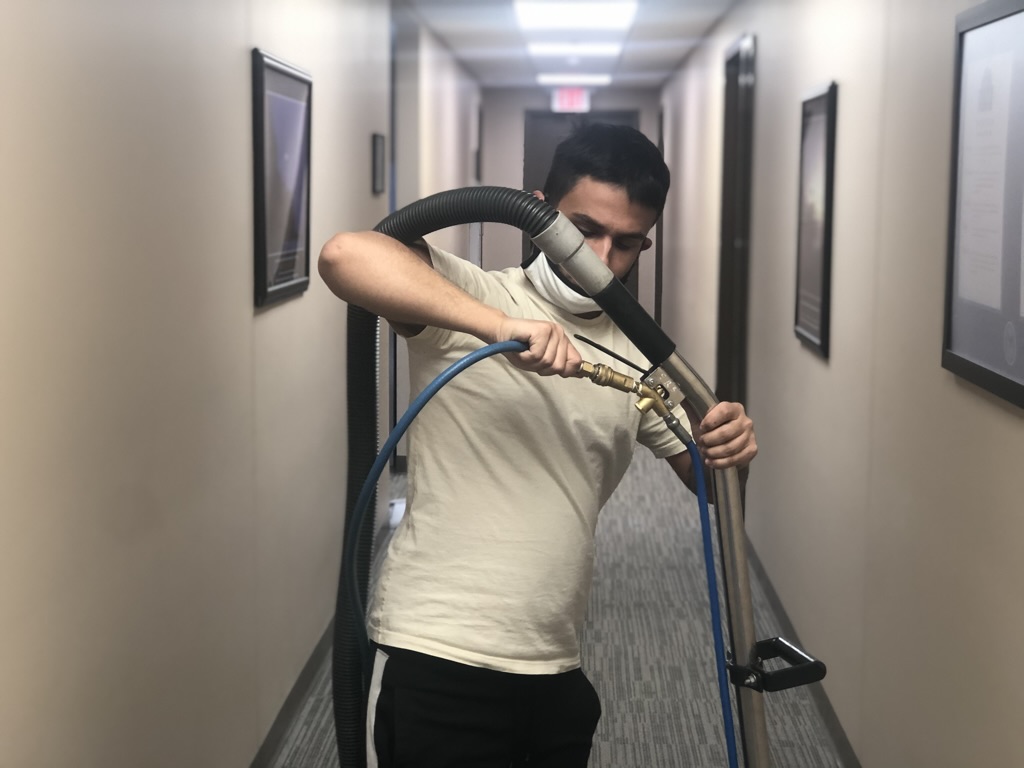 Bel Cleaning technician operating commercial carpet cleaning wand in office hallway — St. Louis, MO