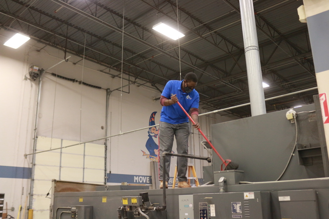 Bel Cleaning technician cleaning the top of elevated industrial equipment