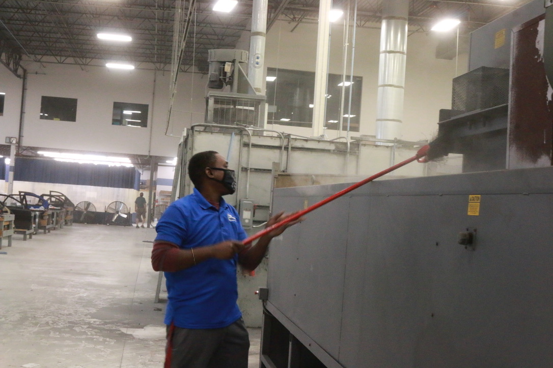 Bel Cleaning worker high dusting tall industrial equipment with extension tool