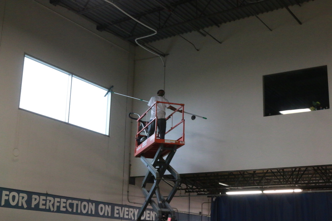 Bel Cleaning worker on a scissor lift cleaning high windows in a St. Louis industrial facility