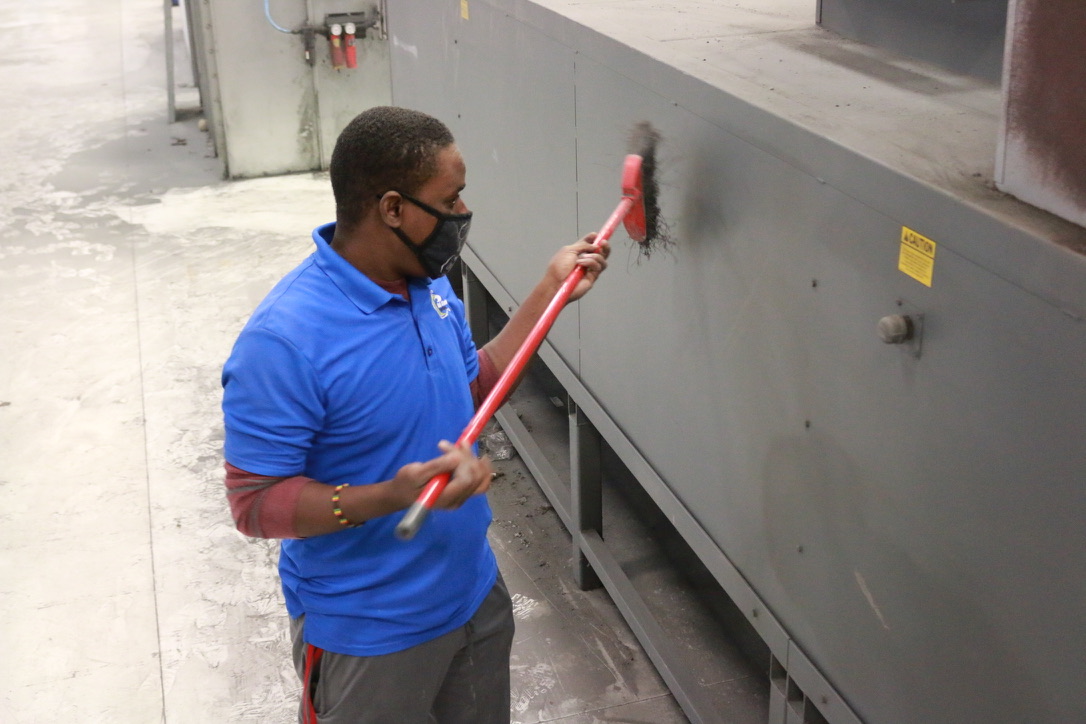 Bel Cleaning crew brushing dust from industrial machinery panels at a Missouri plant