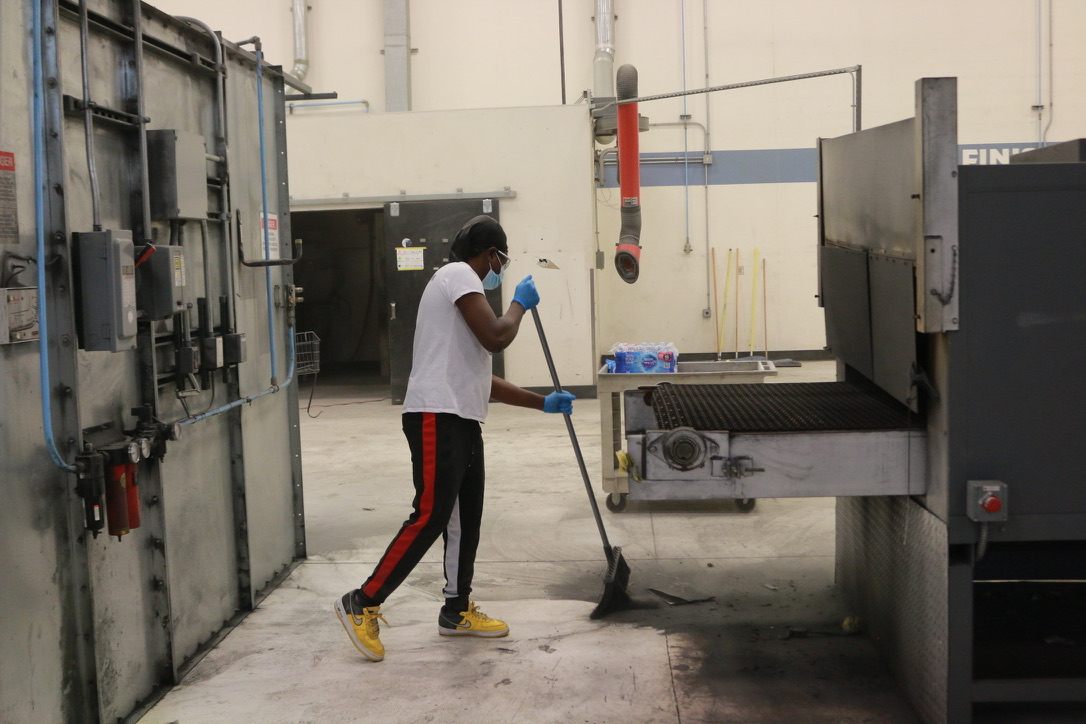 Bel Cleaning crew member cleaning the floor area around a manufacturing conveyor