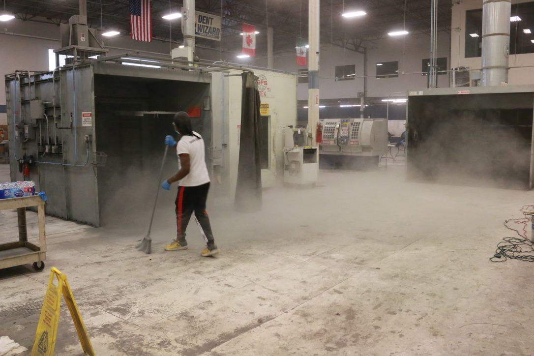 Bel Cleaning crew sweeping dust and debris from a paint booth floor