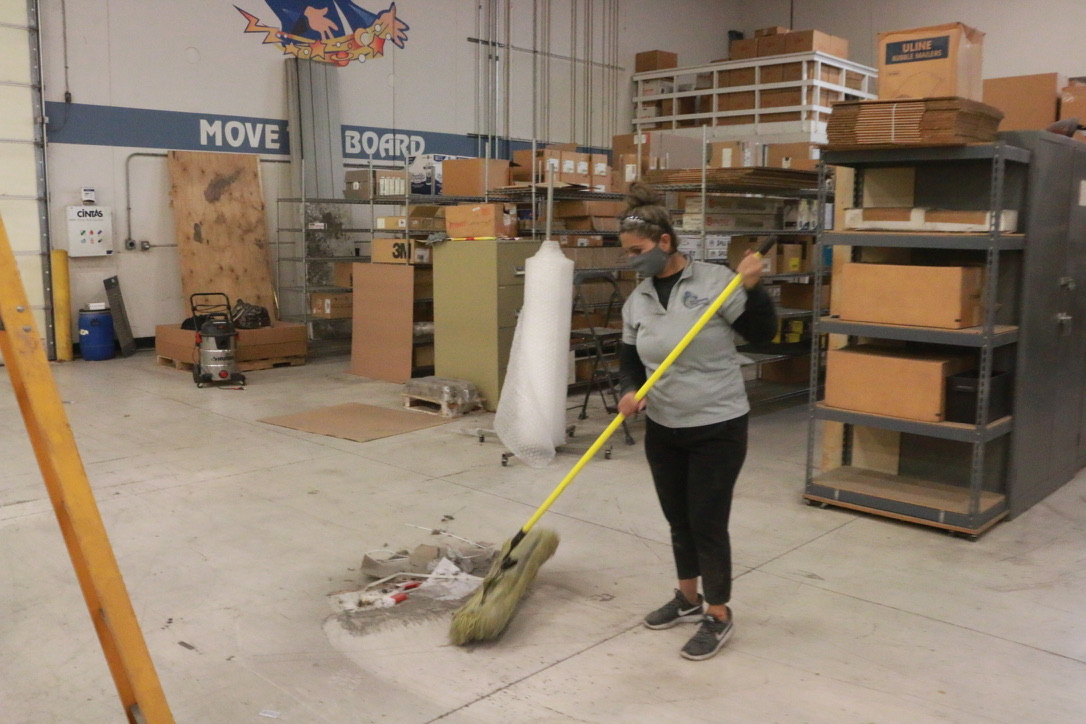 Bel Cleaning technician sweeping debris from a warehouse floor
