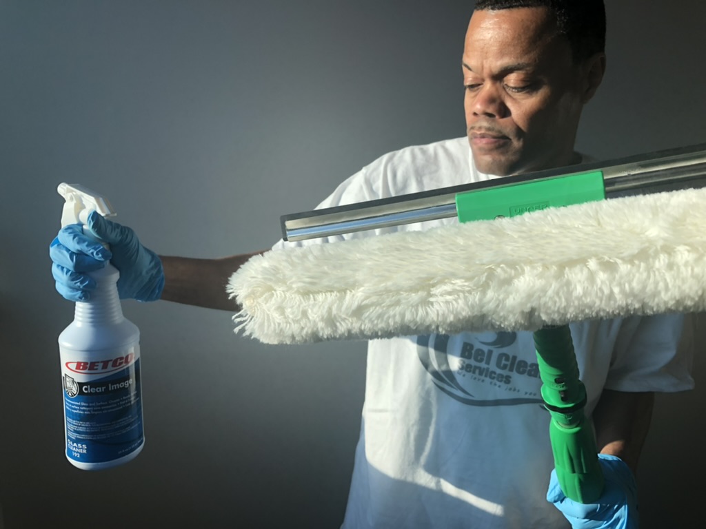 Bel Cleaning technician cleaning a commercial office window with an extension squeegee in St. Louis, MO